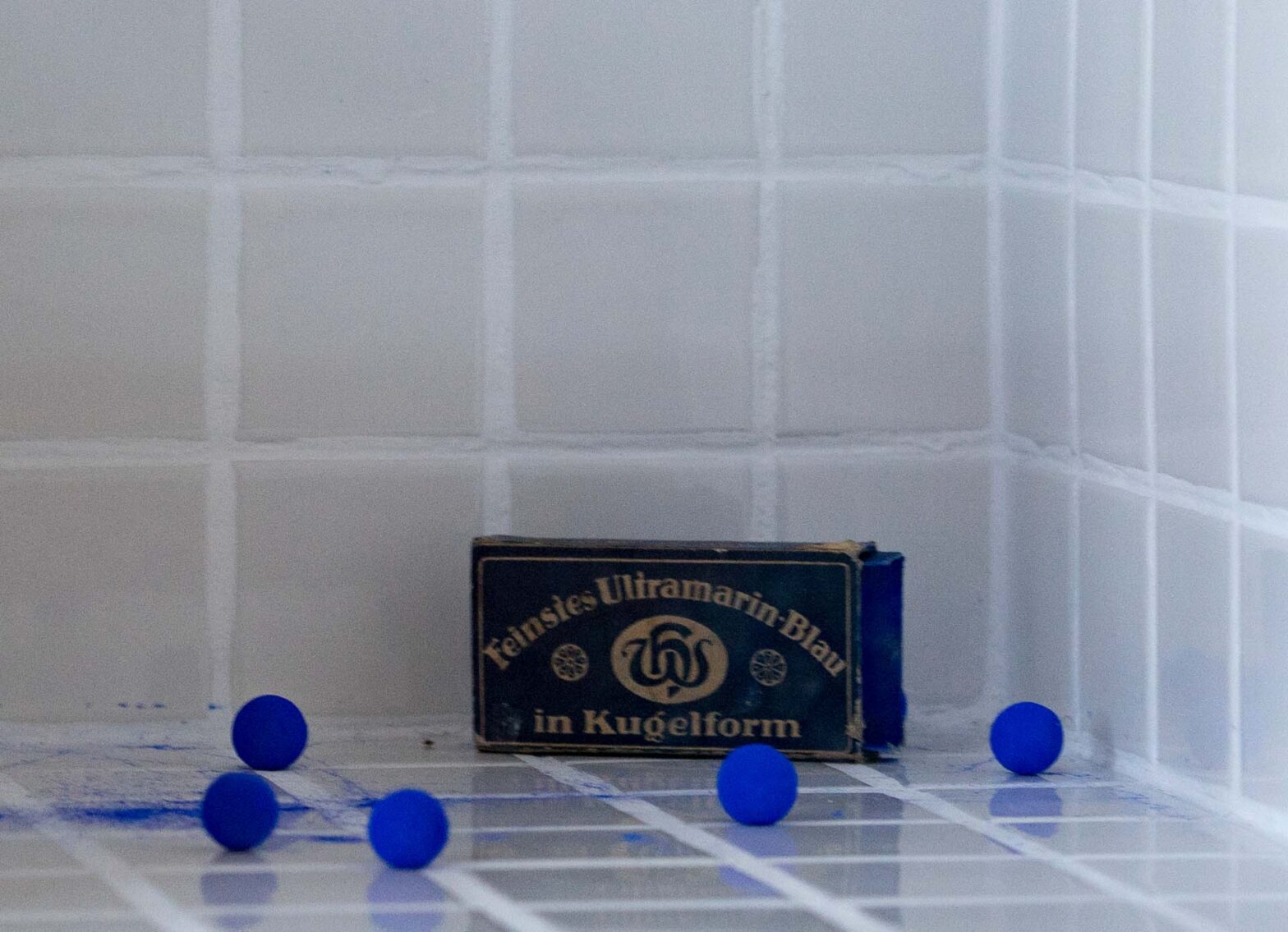 Save the Day – The Day Yves Klein Lost His Marbels in a Laundry (Detail), 2013 Wooden Box, Tiles, Blue Wasching Balls, Glass, Text, 28 x 31 x 31 cm
